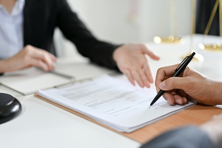 person signing document with a lawyer