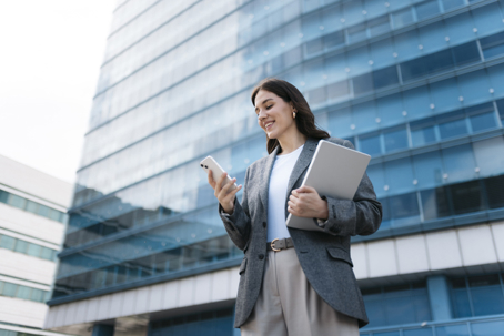 businesswoman checking phone in front of office building
